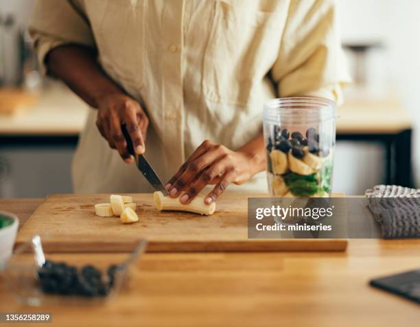 close up of woman hands cutting banana on a cutting board - breakfast woman stockfoto's en -beelden