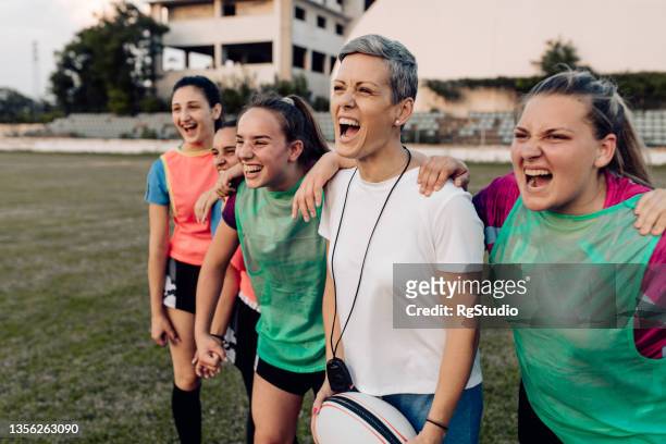 des filles heureuses d’une équipe de rugby célébrant le succès avec leur entraîneur - stade rugby photos et images de collection