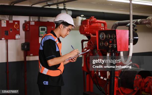 joven ingeniero revisa el sistema de extinción de incendios en la sala de control de la fábrica, el trabajo de verificación diaria del técnico de mantenimiento - safety fotografías e imágenes de stock