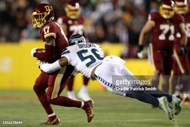 Terry McLaurin of the Washington Football Team caries the ball as Jordyn Brooks of the Seattle Seahawks defends in the first quarter of the game at...