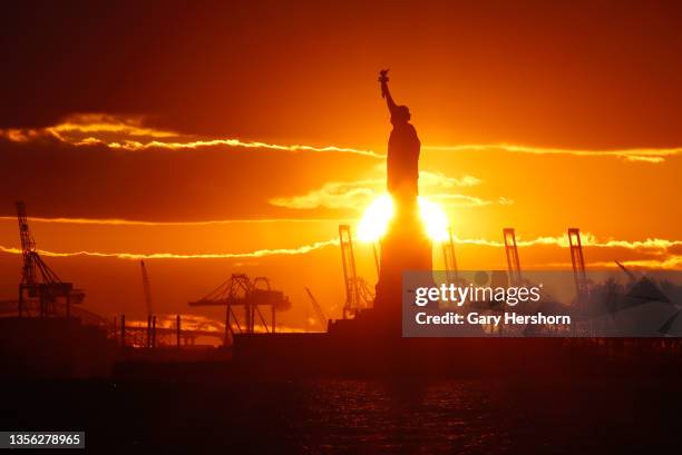 The sun sets behind the Statue of Liberty seen from The Battery on November 29 in New York City.