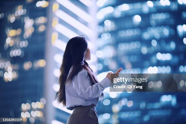 young asian woman standing in shanghai financial district using her smartphone - shanghai calling stock pictures, royalty-free photos & images