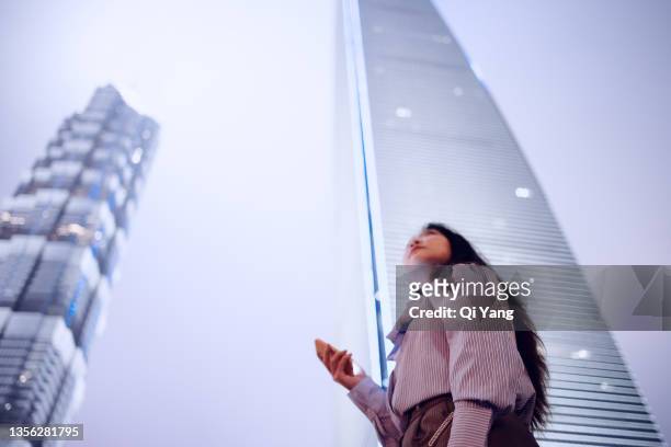 young asian business woman using smartphone in famous landmark of pudong district, shanghai - fintech stock-fotos und bilder