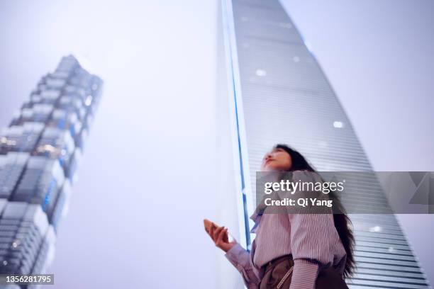 young asian business woman using smartphone in famous landmark of pudong district, shanghai - vp marketing fotografías e imágenes de stock
