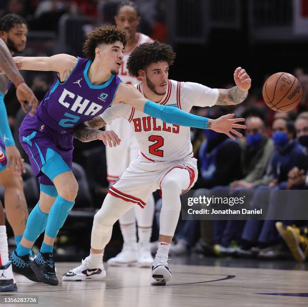 LaMelo Ball of the Charlotte Hornets and brother Lonzo Ball of the Chicago Bulls chase a loose ball at United Center on November 29, 2021 in Chicago,...