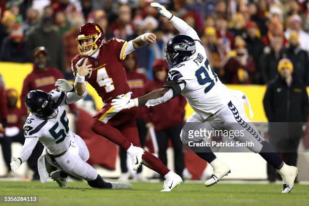 Taylor Heinicke of the Washington Football Team carries the ball as Poona Ford and Ryan Neal of the Seattle Seahawks defend in the second quarter of...