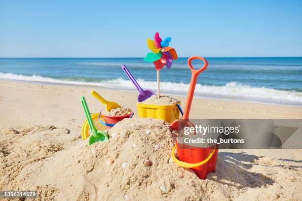 still life of colorful beach toys and sand castle at sea against blue sky - château de sable photos et images de collection