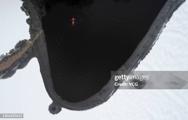 Aerial view of a winter swimmer swimming in a frozen lake after a snowfall at Beiling Park on November 30, 2021 in Shenyang, Liaoning Province of...