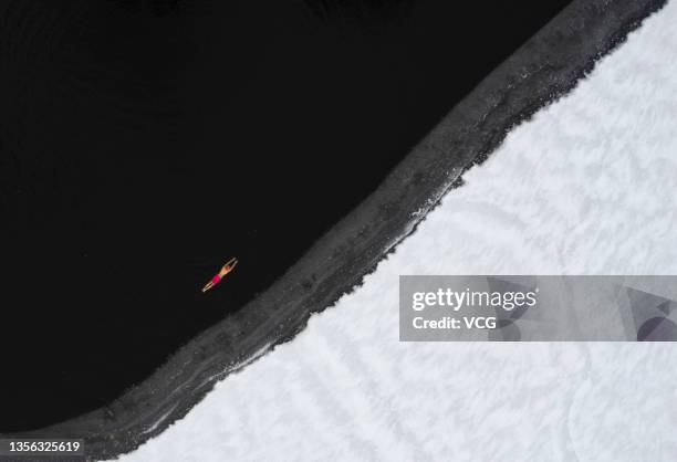 Aerial view of a winter swimmer swimming in a frozen lake after a snowfall at Beiling Park on November 30, 2021 in Shenyang, Liaoning Province of...