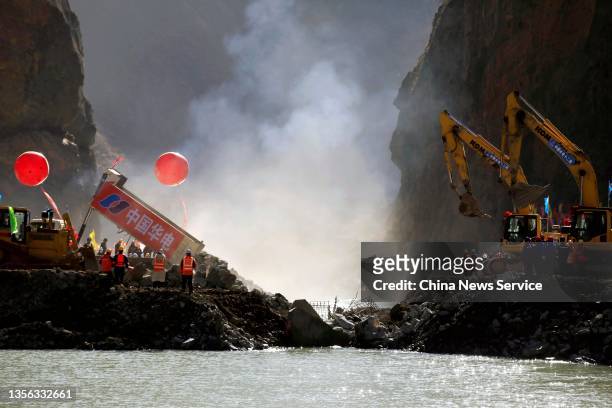 Trucks dump rocks to compete the river closure during the construction of Lawa Hydropower Station at the upper reaches of the Jinsha River on...