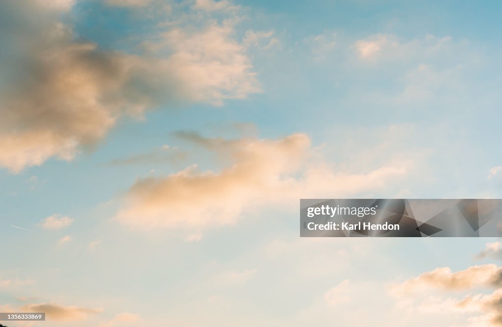 A view of pink clouds against a blue sky at sunset - stock photo