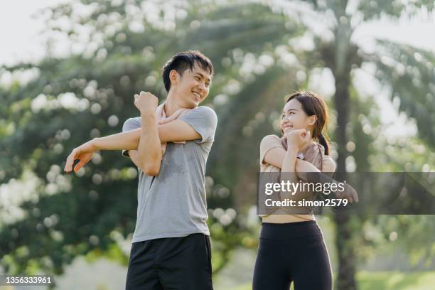 happy young man and woman stretching in the park - warm up exercise stock pictures, royalty-free photos & images