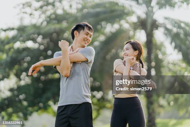 happy young man and woman stretching in the park - asian couple imagens e fotografias de stock