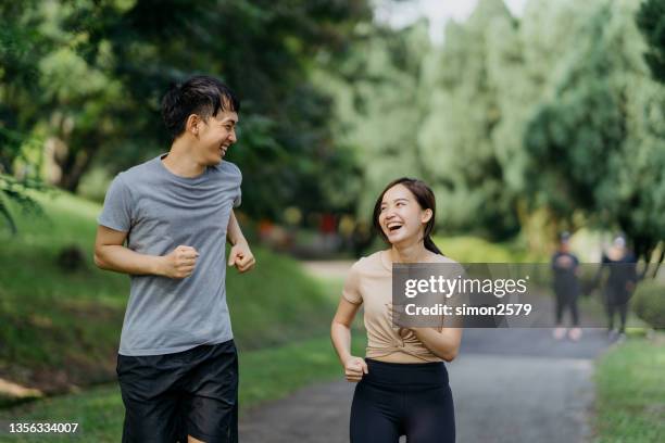 healthy asian couple jogging in public park - asian young couple stock pictures, royalty-free photos & images