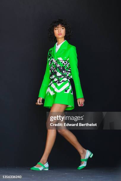 Model wears a white shirt, a neon green with black and white print pattern leather jacket, a matching neon green with black and white print pattern...