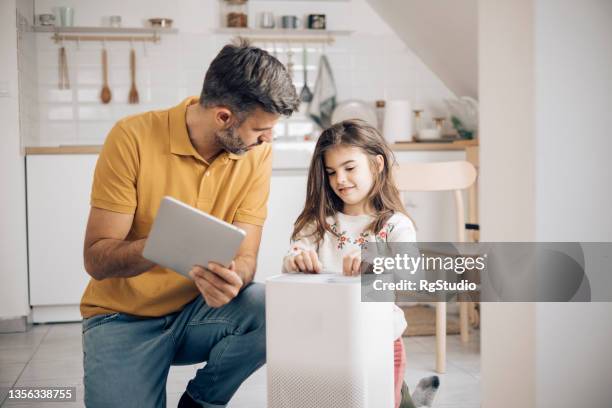 mann und seine kleine tochter schalten ihren luftbefeuchter für zu hause mit einem intelligenten system ein - luftfilter stock-fotos und bilder