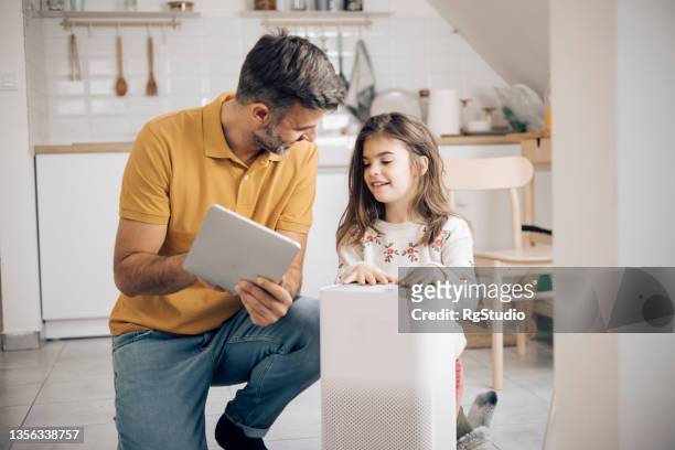 niña y su padre usando una tableta digital para encender el filtro de aire - air purifier fotografías e imágenes de stock