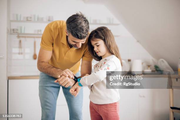 papá enseñando a su pequeña hija a usar un reloj inteligente - reloj inteligente fotografías e imágenes de stock