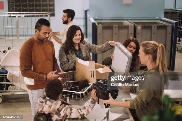 parents with children exchanging electronic waste at recycling center - circulaire economie stockfoto's en -beelden