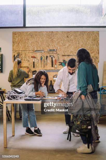 girl and male worker repairing electronics at table in recycling center - recycling center ストックフォトと画像