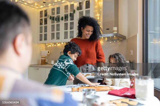 sorella e fratello che fanno i biscotti di pan di zenzero di natale con una madre - famiglia cucina foto e immagini stock