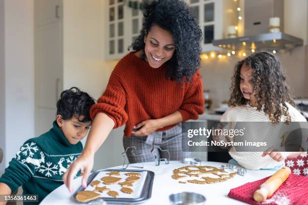 sœur et frère faisant des biscuits au pain d’épices de noël avec une mère - faire cuire au four photos et images de collection
