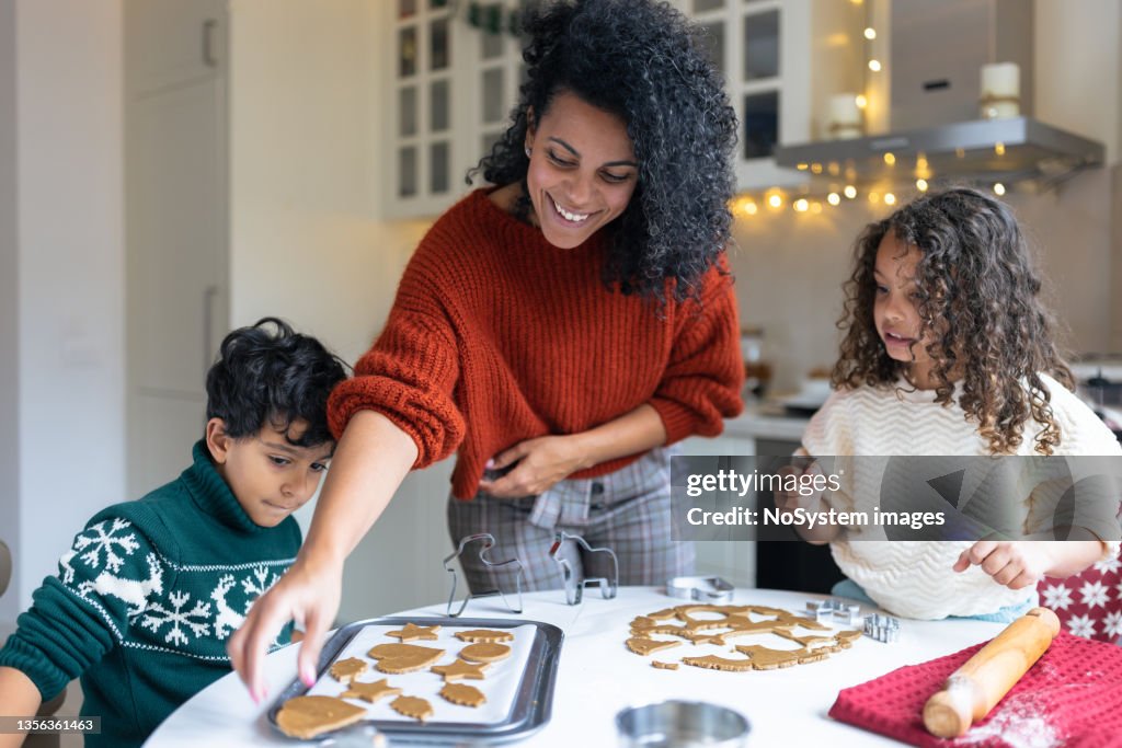 Sister and brother making Christmas gingerbread cookies with a mother