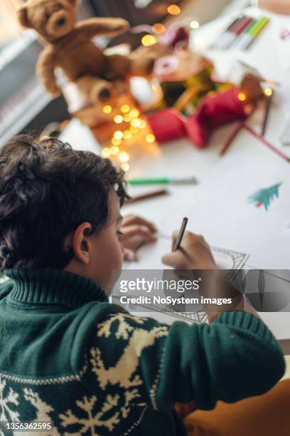junge zeichnet eine weihnachtswunschliste - christmas list stock-fotos und bilder