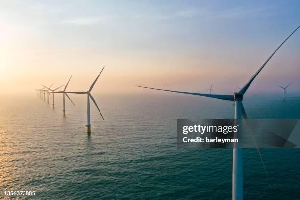 row of winturbines in the sea - offshore windfarm stock-fotos und bilder