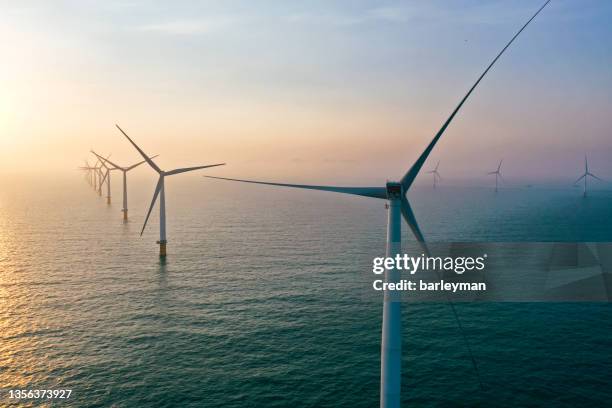 row of winturbines in the sea - offshore windfarm stock-fotos und bilder