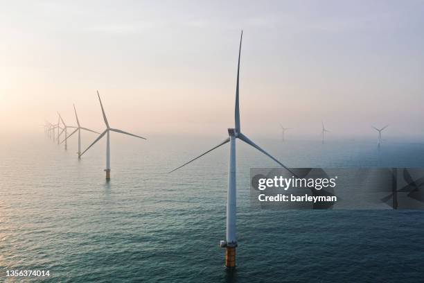 row of winturbines in the sea - offshore windfarm stock-fotos und bilder