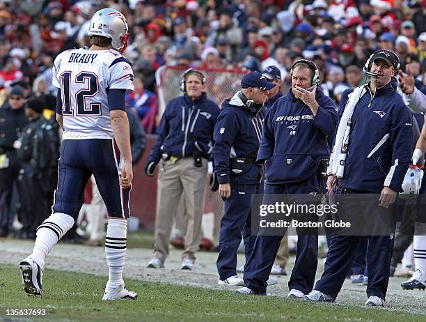 Patriots quarterback Tom Brady walks towards the bench as head coach Bill Belichick, center, and offensive coordinator Bill O'Brien watch. He New...