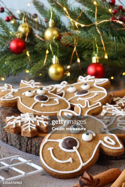 nahaufnahme eines kühlregals mit hausgemachten, lebkuchen-rentierkeksen, verziert mit weißer königlicher glasur, rot-goldenen kugeln auf mini-weihnachtsbaum, zimtstangen, sternanis, hellblauem hintergrund, fokus im vordergrund - rack focus stock-fotos und bilder