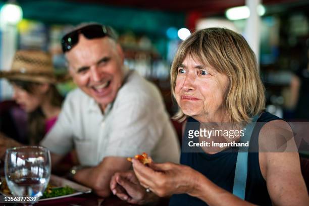 senior woman tries a new dish in a restaurant. - provar imagens e fotografias de stock