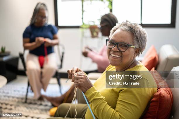 porträt einer älteren frau, die zu hause strickt - knitting stock-fotos und bilder