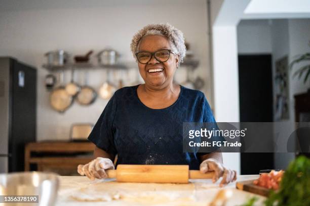 porträt einer seniorin, die zu hause backt - woman baking stock-fotos und bilder