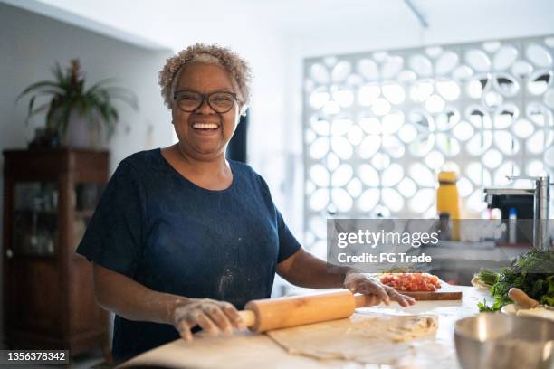 portrait of a senior woman baking at home - women baking stock pictures, royalty-free photos & images