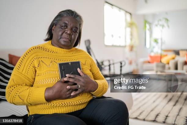 portrait of a senior woman holding a photo and missing someone at home - missing persons stock pictures, royalty-free photos & images