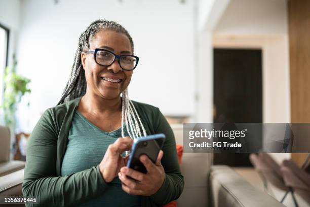 portrait of a senior woman using a mobile phone at home - at home portrait stockfoto's en -beelden