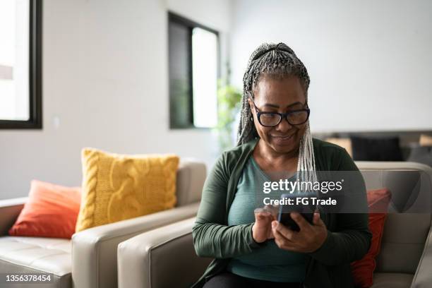 senior woman using a mobile phone at home - adult phone stock pictures, royalty-free photos & images
