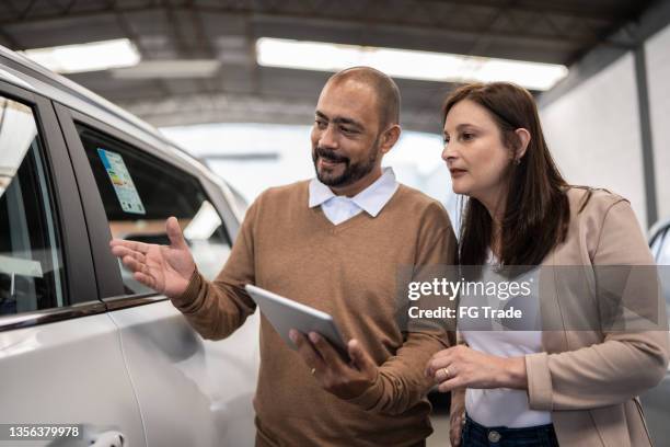 salesman showing car to customer in a car dealership - car salesman stock pictures, royalty-free photos & images