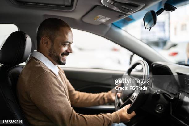 hombre maduro admirando un coche nuevo en un showroom - car ownership fotografías e imágenes de stock
