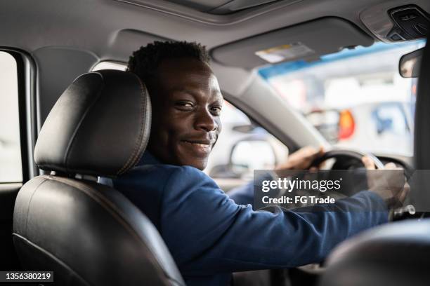 portrait of a young man choosing new car in car dealership - uber stockfoto's en -beelden