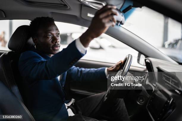 customer adjusting rear view mirror in car in a car dealership - chauffeur 個照片及圖片檔