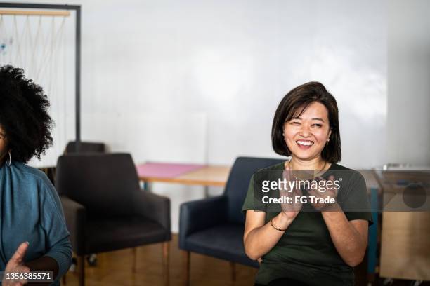 businesswoman clapping in group therapy or a business meeting - employee welfare stockfoto's en -beelden