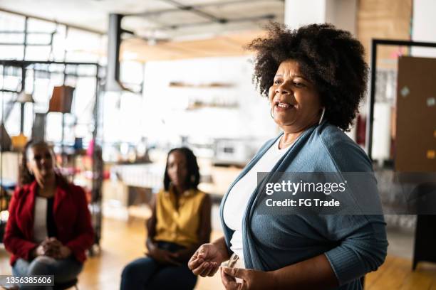 mature woman talking in a meeting or group therapy - community center stock pictures, royalty-free photos & images