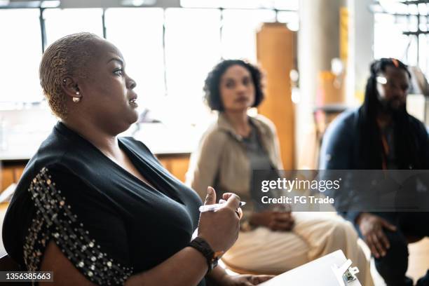 mid adult woman talking in a meeting or group therapy - employee welfare stockfoto's en -beelden