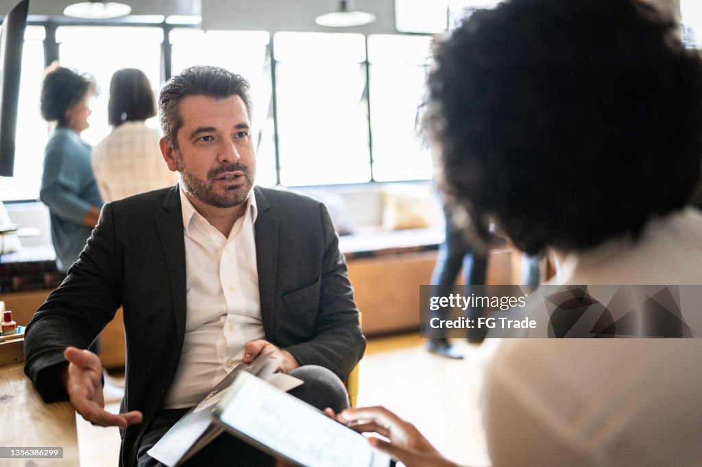 Mature man talking with a colleague at work