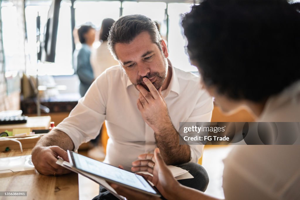 Mature man looking at a digital tablet that a colleague is showing at work
