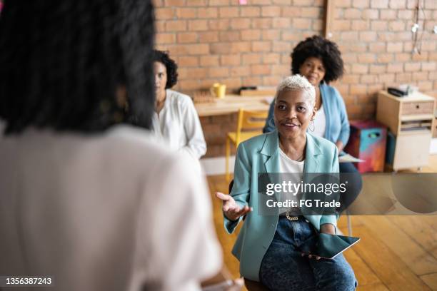 business woman making a question to speaker in a conference - participant guide stock pictures, royalty-free photos & images